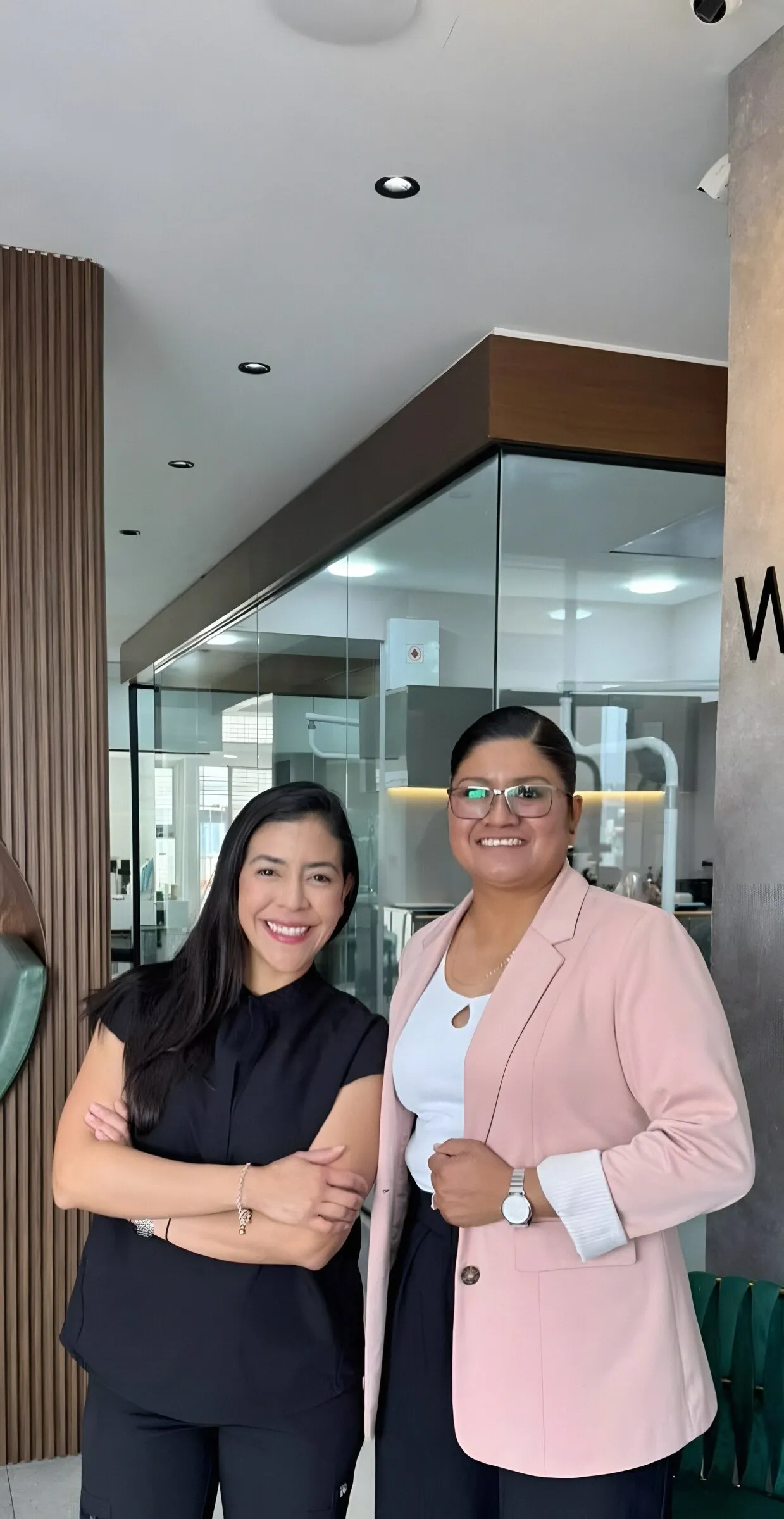 Dos integrantes del equipo frente a los consultorios con paredes de vidrio y madera